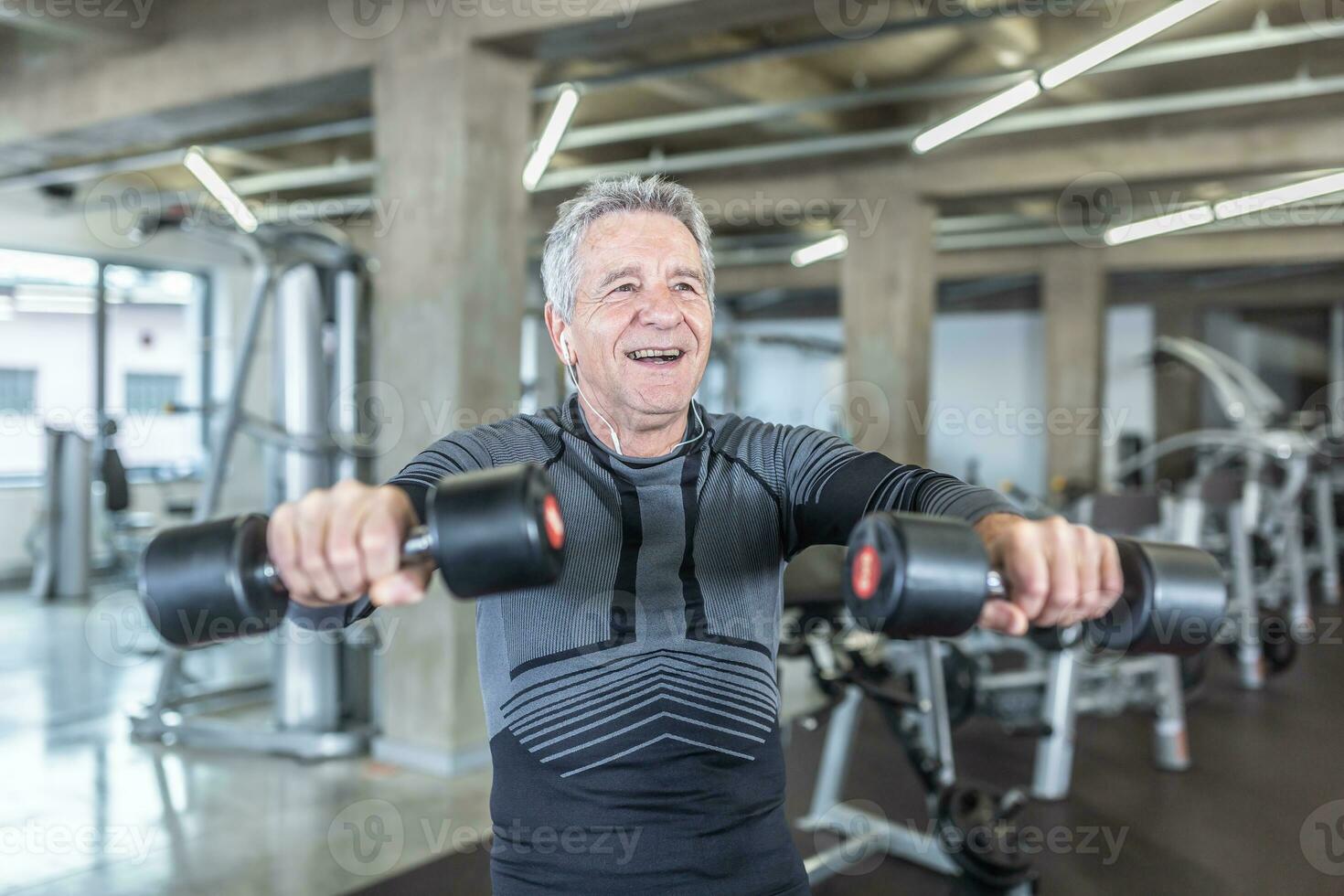 maschio nel il suo 60s gode dumbell allenarsi nel il fitness centro foto