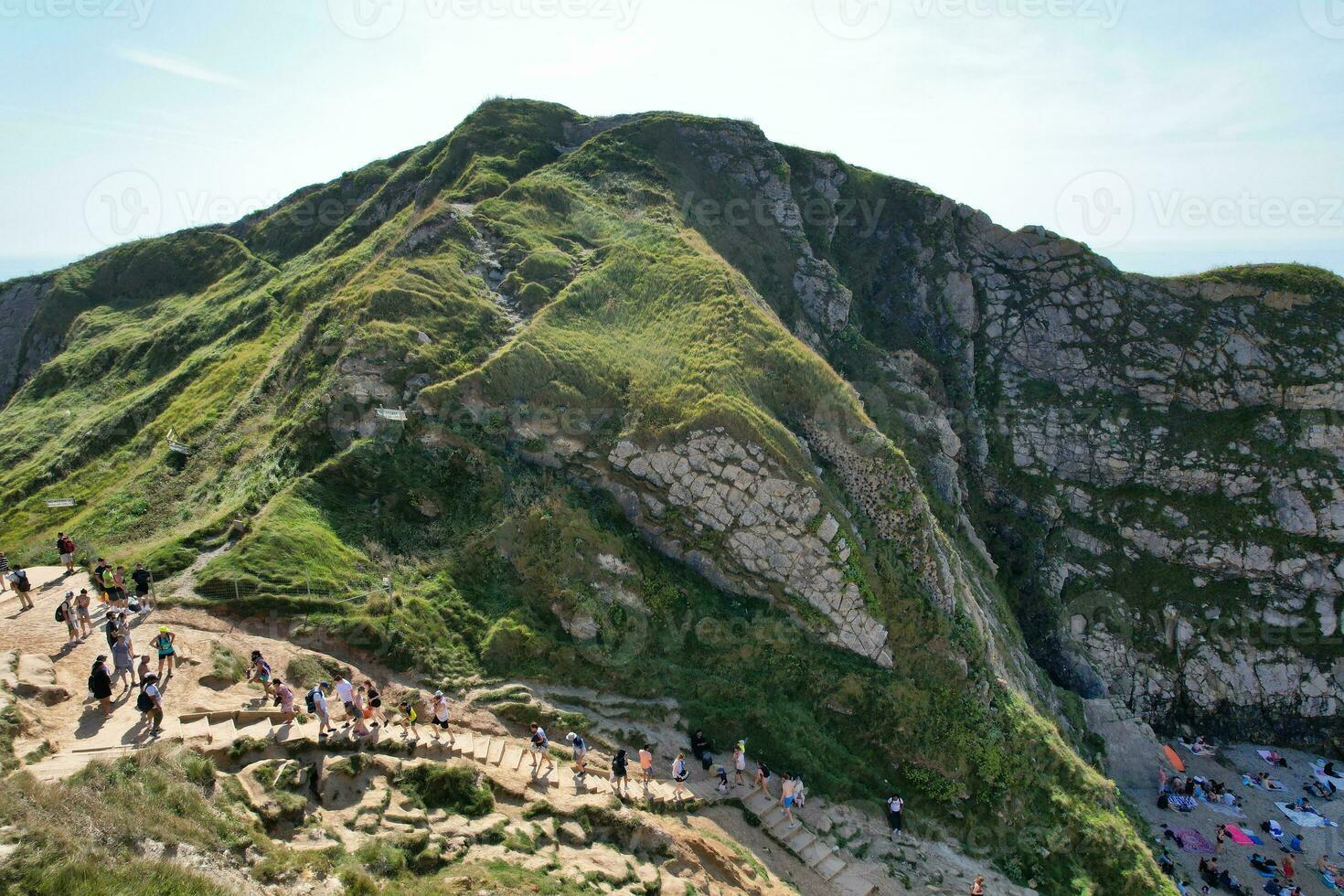 alto angolo Visualizza di persone siamo si avvicina per durdle porta spiaggia quale è maggior parte famoso turista attrazione posto attraverso a piedi distanza al di sopra di paesaggio e colline. catturato su settembre 9, 2023 foto