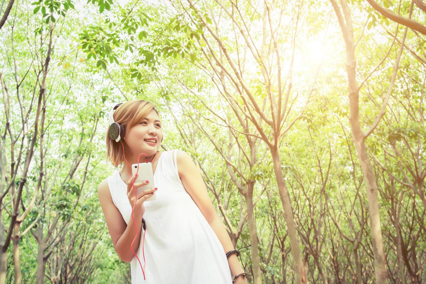 concetto di stile di vita giovane donna asiatica che ascolta godendo la musica nella foresta foto