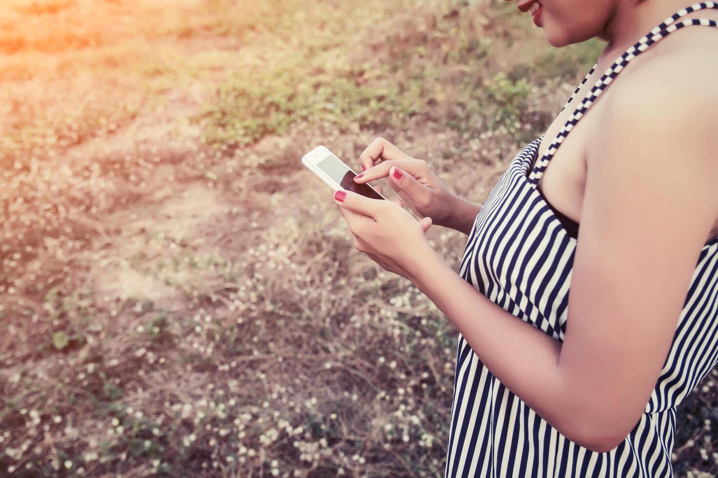 mani di donna che utilizzano uno smartphone in un campo di fiori in estate foto
