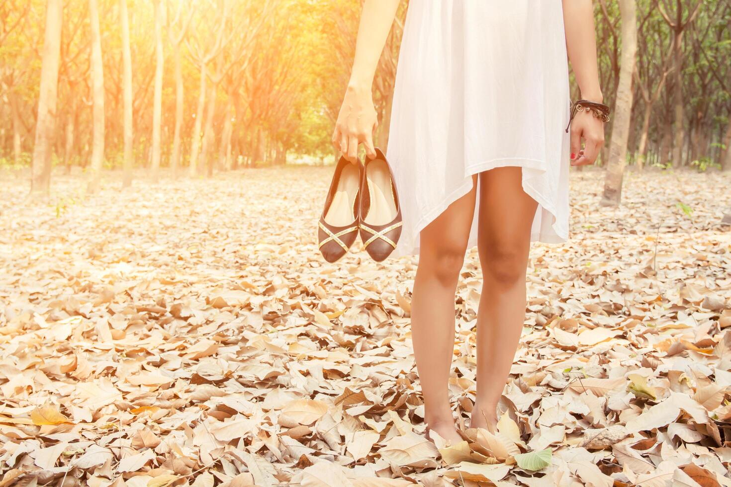 giovane donna che porta le scarpe quando è stanca di camminare nella foresta foto