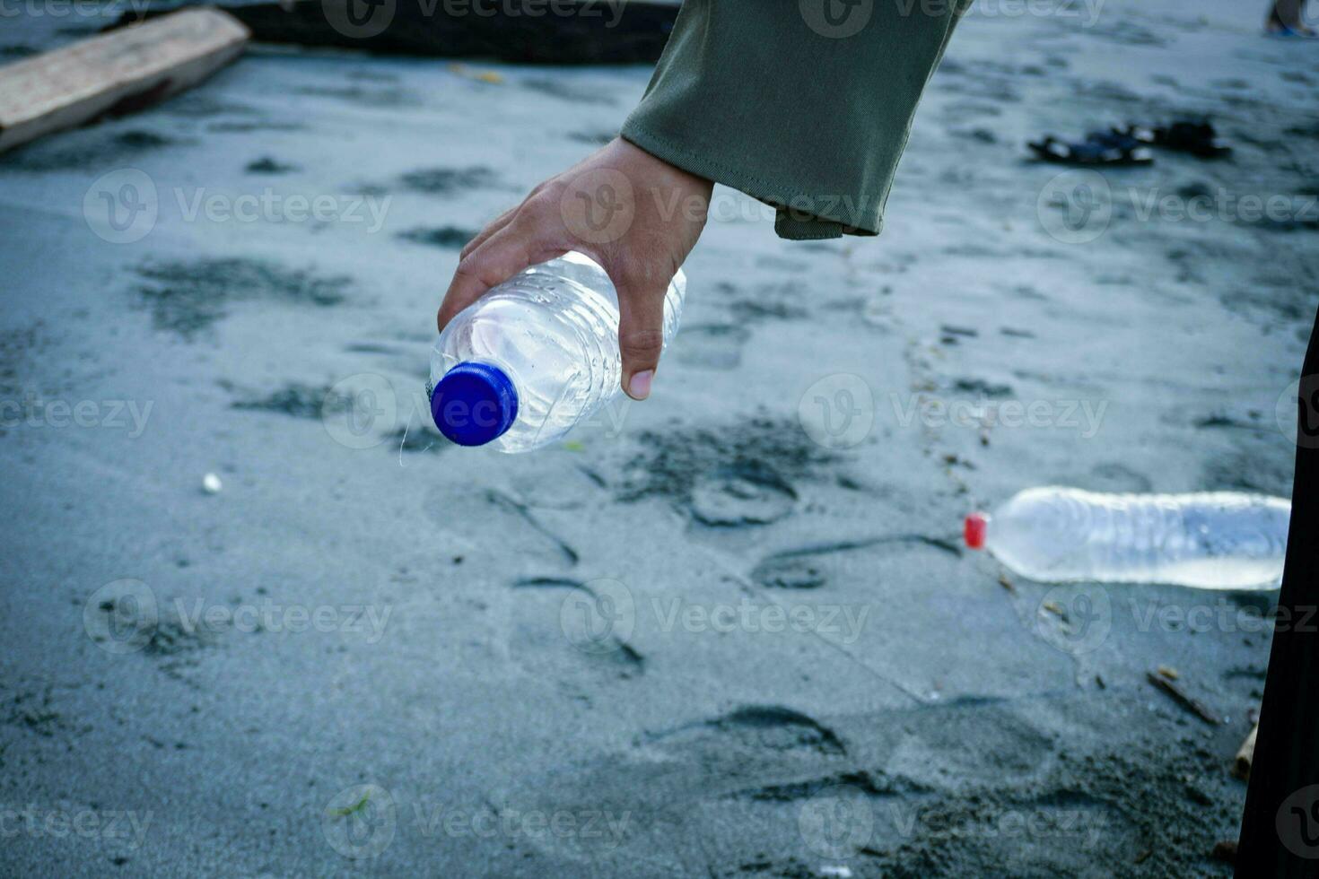 mano donna raccolta su plastica bottiglia pulizia su il spiaggia , volontario concetto foto