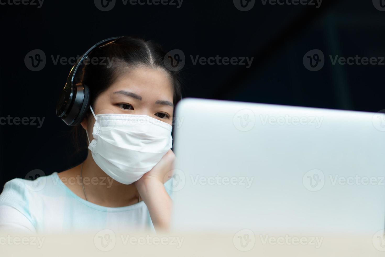 youwoman che indossa la maschera e usa la videoconferenza del computer foto