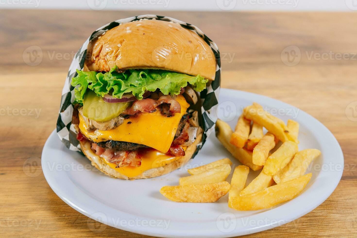 delizioso fatti in casa Hamburger su un' piatto su un' di legno tavolo. grande hamburger al formaggio con francese patatine fritte servito su di legno tavolo foto