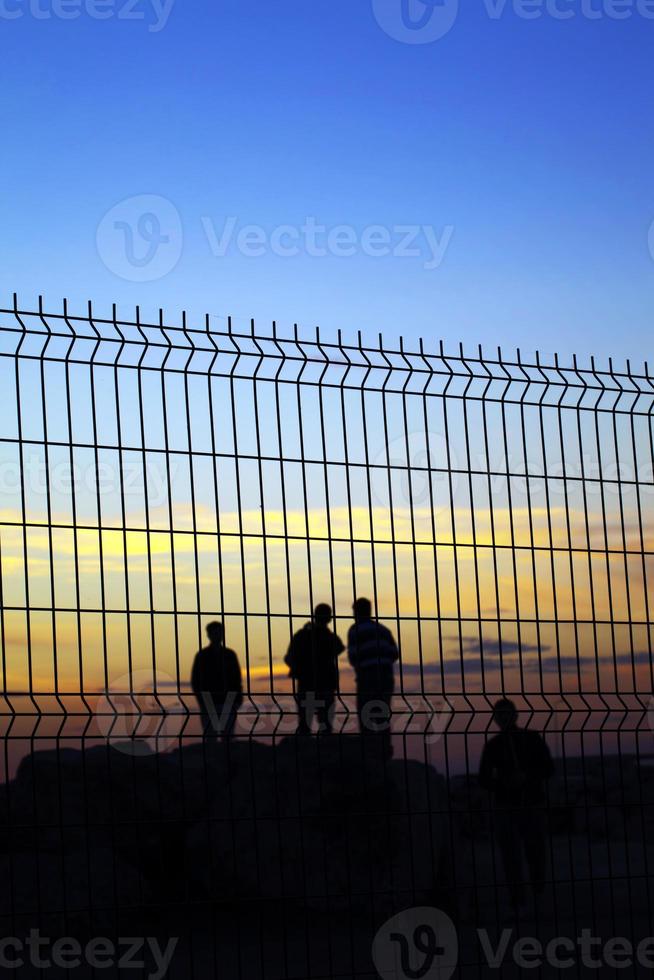 silhouette di persone dietro il recinto della grata foto