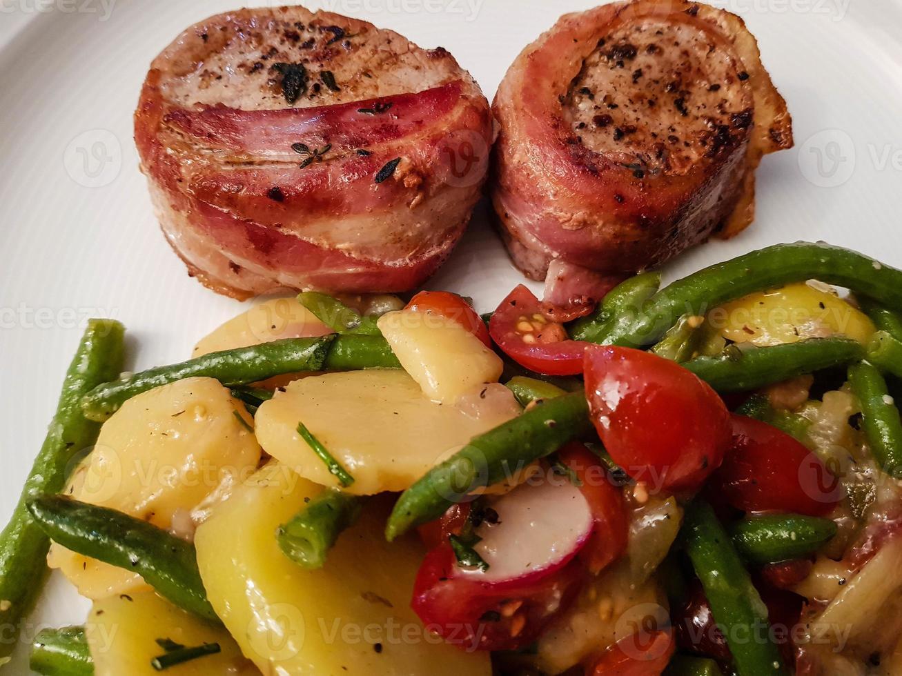 filetto di maiale avvolto in pancetta e insalata foto