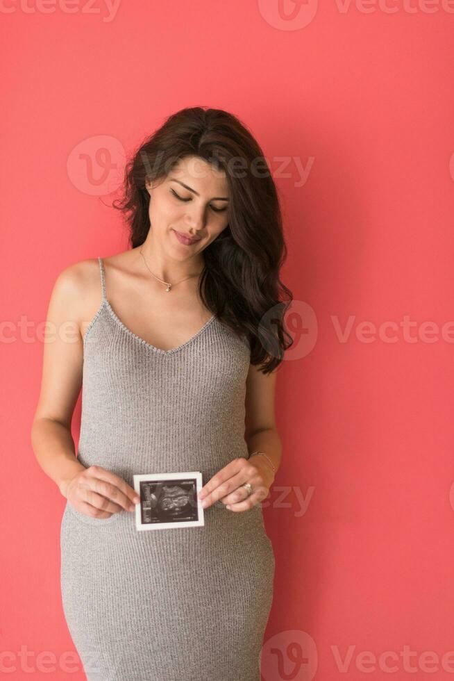 felice donna incinta che mostra un'immagine ecografica foto