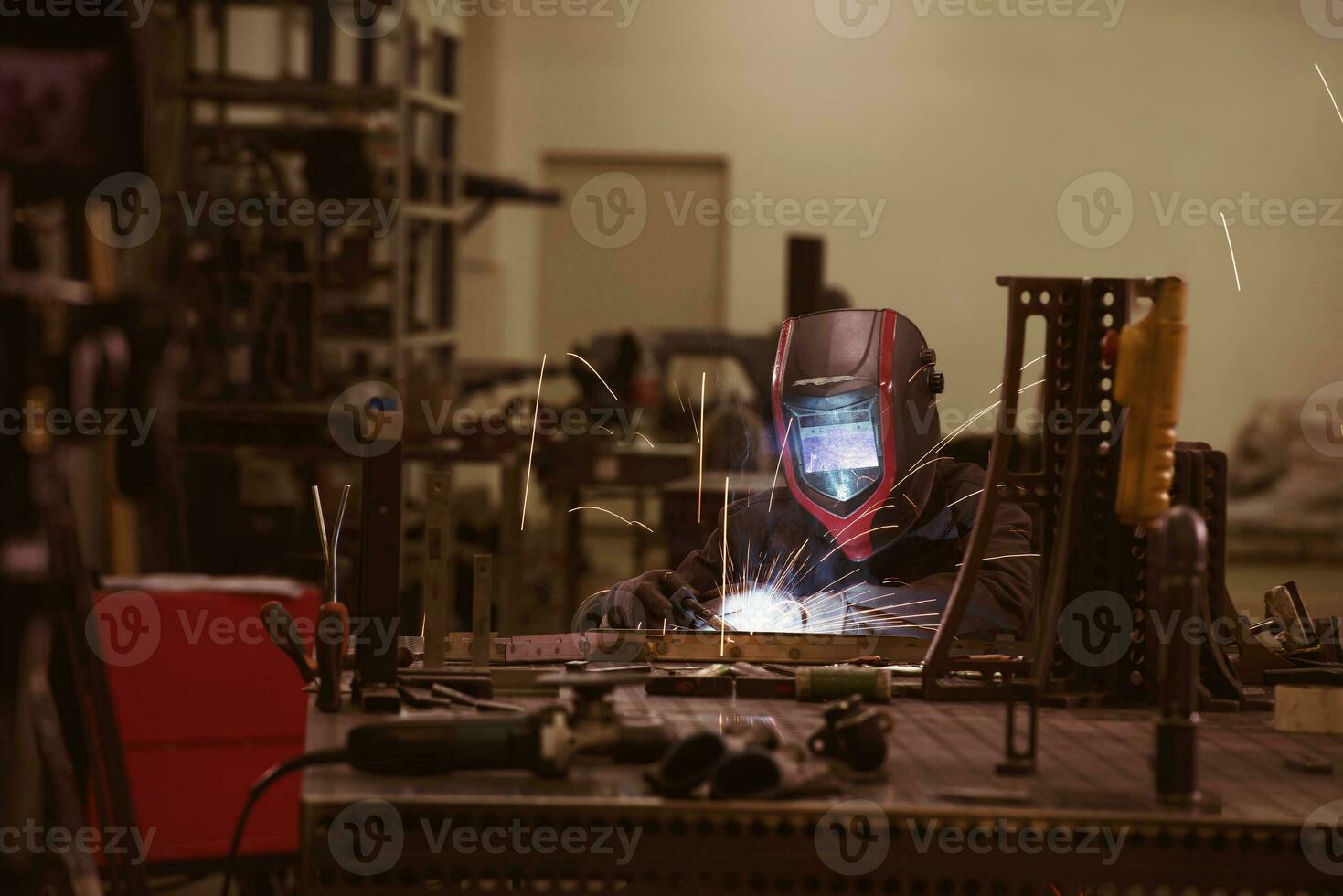 saldatore professionista dell'industria pesante che lavora all'interno della fabbrica, indossa il casco e inizia a saldare. messa a fuoco selettiva foto