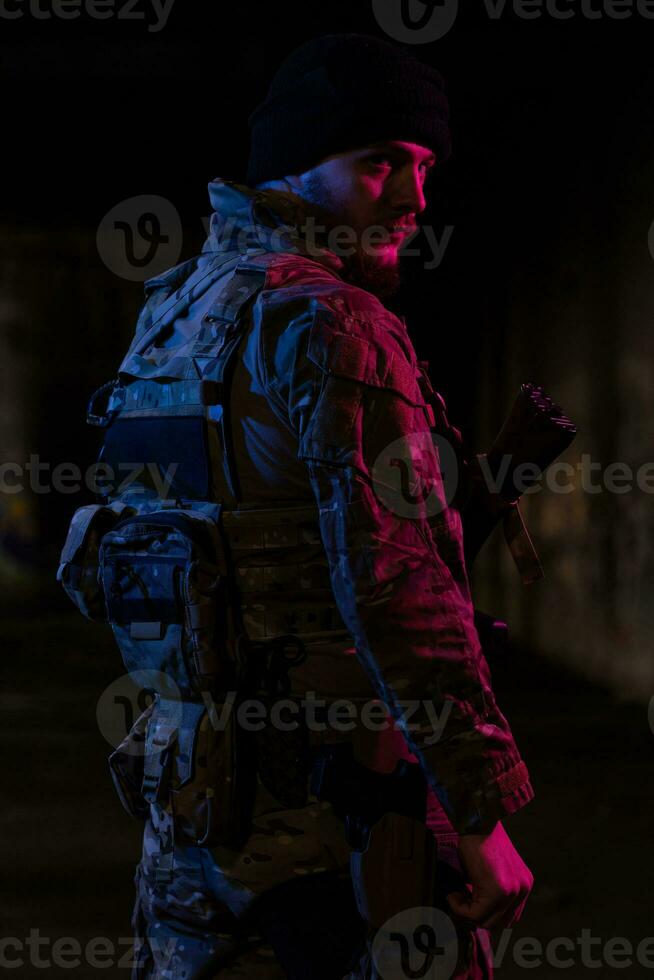 esercito soldato nel combattere uniformi con un assalto fucile e combattere casco notte missione buio sfondo. blu e viola gel leggero effetto. foto