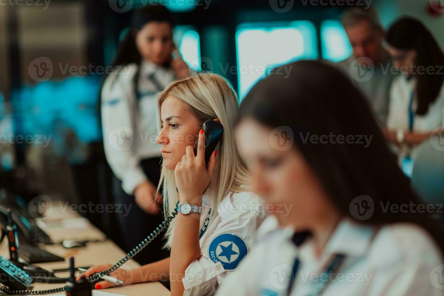 femmina sicurezza guardia operatore parlando su il Telefono mentre Lavorando a stazione di lavoro con multiplo viene visualizzato sicurezza guardie ✔ Lavorando su multiplo monitor foto