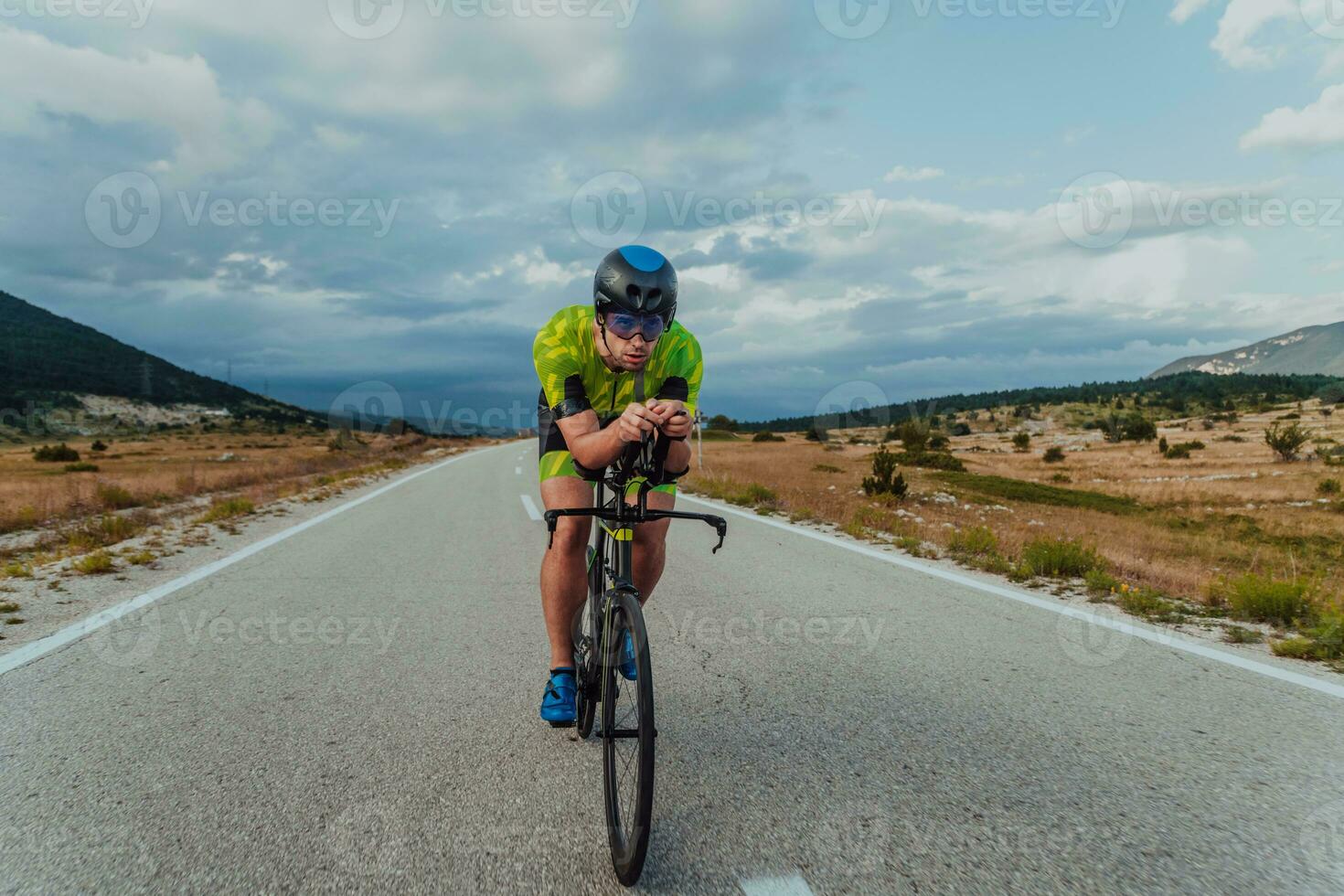 pieno lunghezza ritratto di un attivo triatleta nel abbigliamento sportivo e con un' protettivo casco equitazione un' bicicletta. selettivo messa a fuoco foto