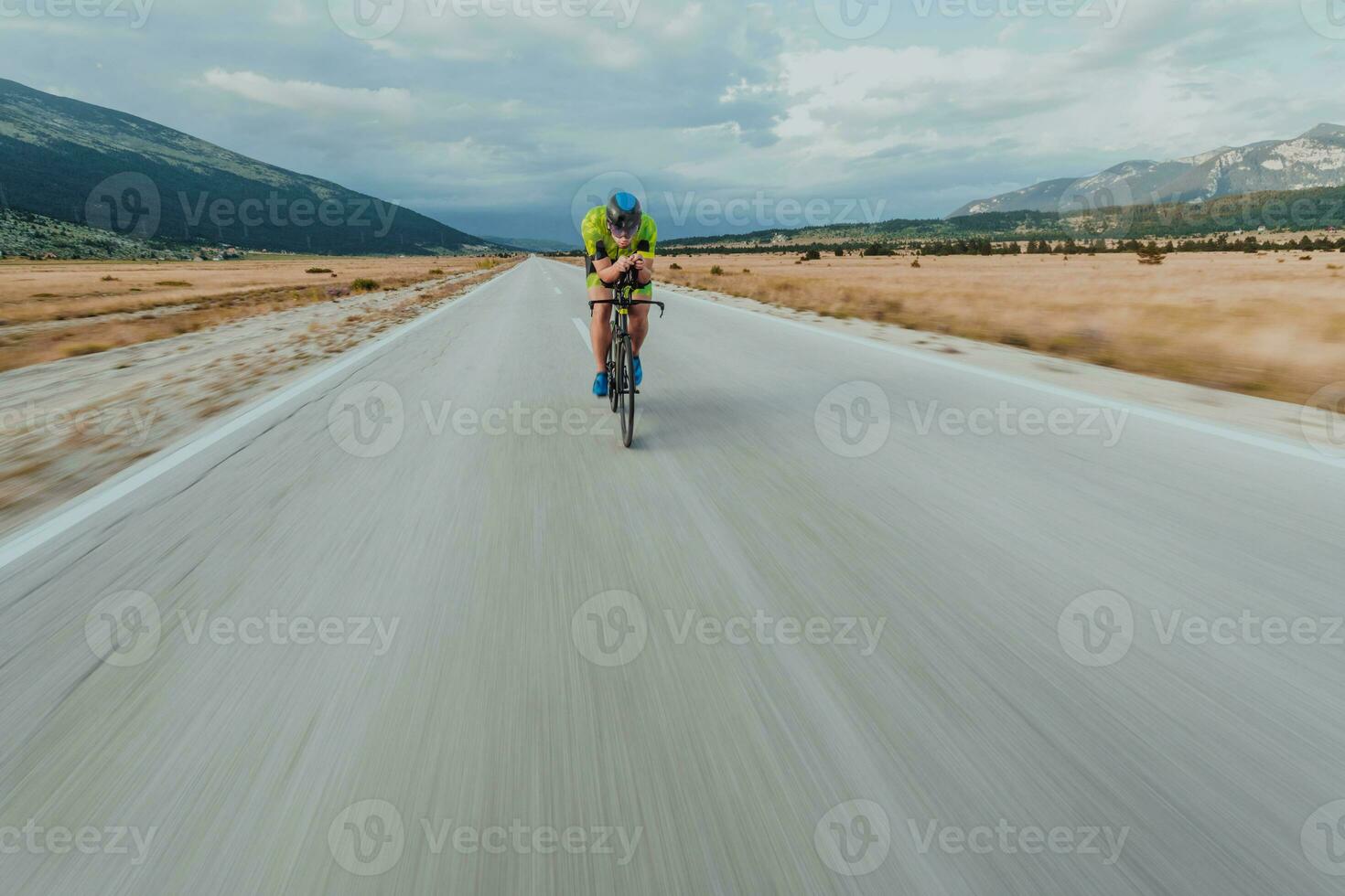 pieno lunghezza ritratto di un attivo triatleta nel abbigliamento sportivo e con un' protettivo casco equitazione un' bicicletta. selettivo messa a fuoco foto