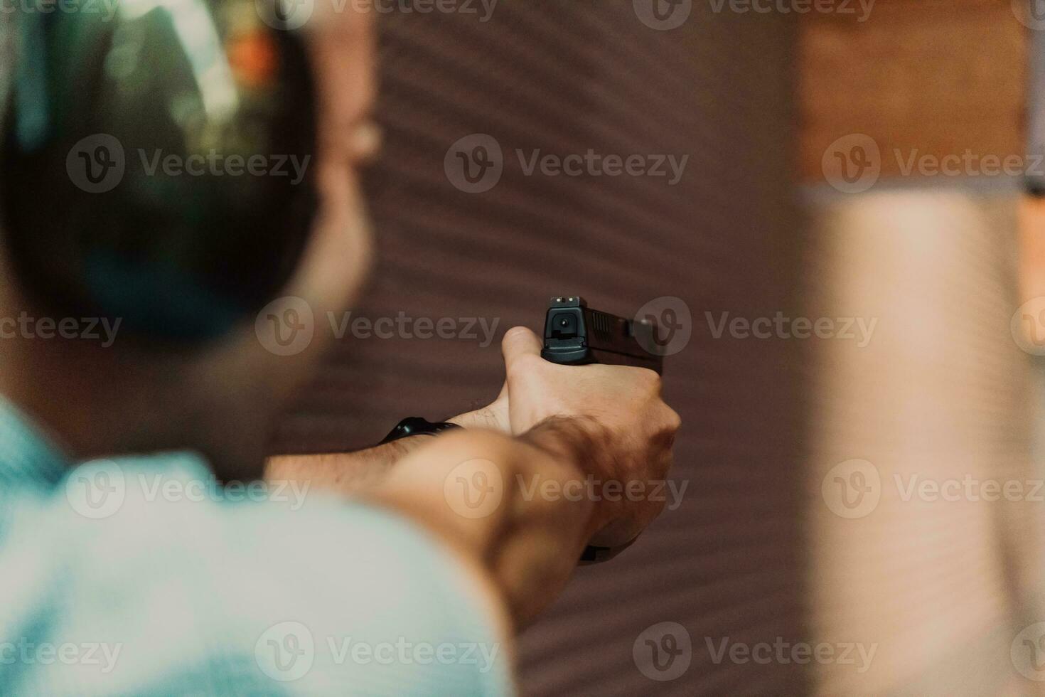 un' uomo pratiche tiro un' pistola nel un' tiro gamma mentre indossare protettivo cuffie foto