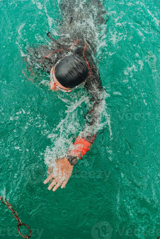un' triatleta nel un' professionale nuoto completo da uomo treni su il fiume mentre preparazione per olimpico nuoto foto