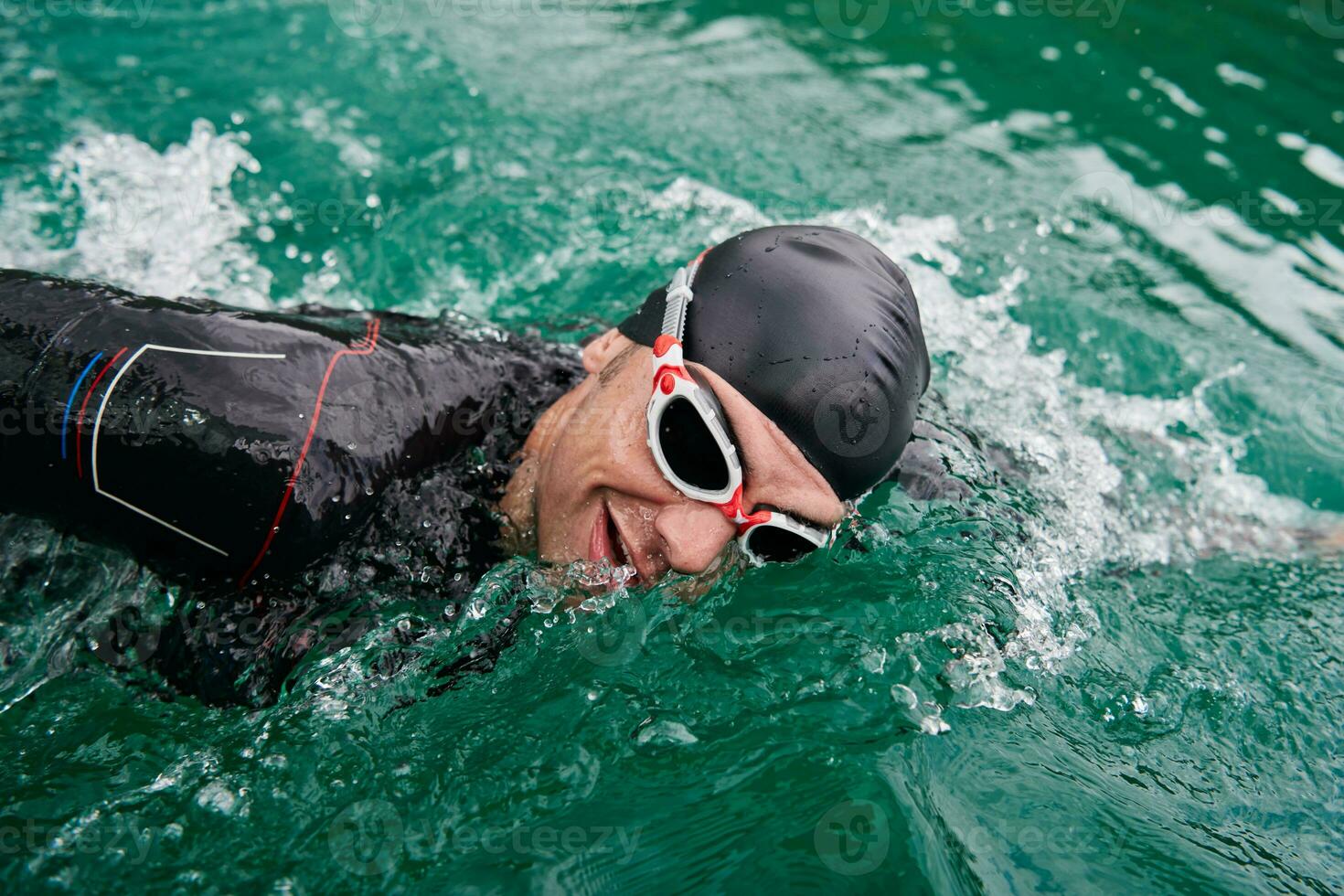 atleta di triathlon che nuota sul lago indossando la muta foto