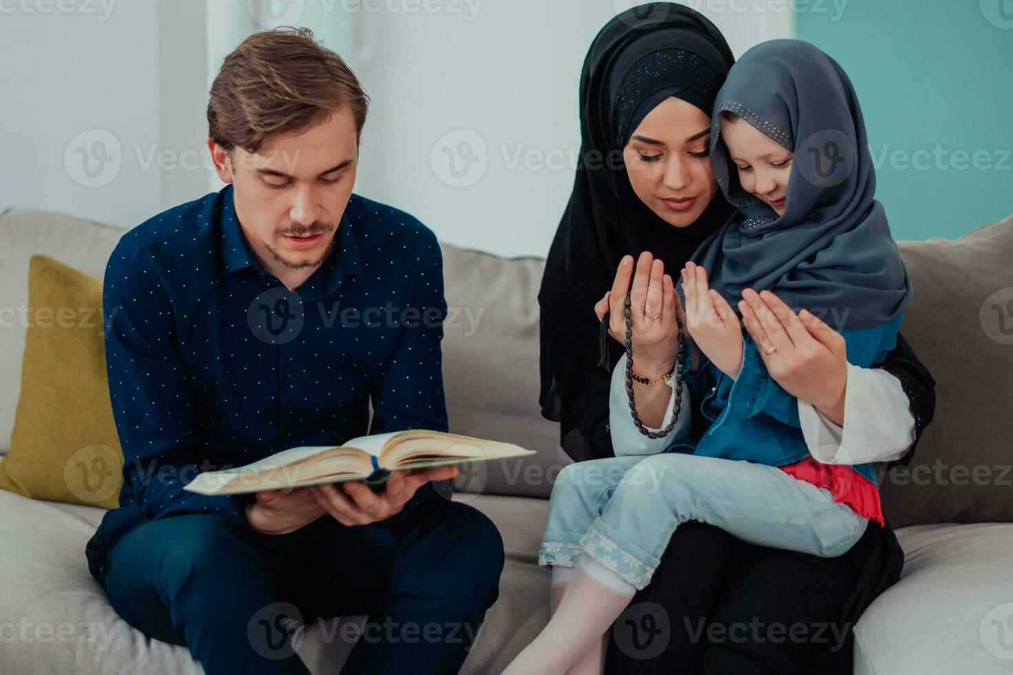 contento musulmano famiglia godendo il santo mese di Ramadan mentre preghiere e lettura il Corano insieme nel un' moderno casa foto