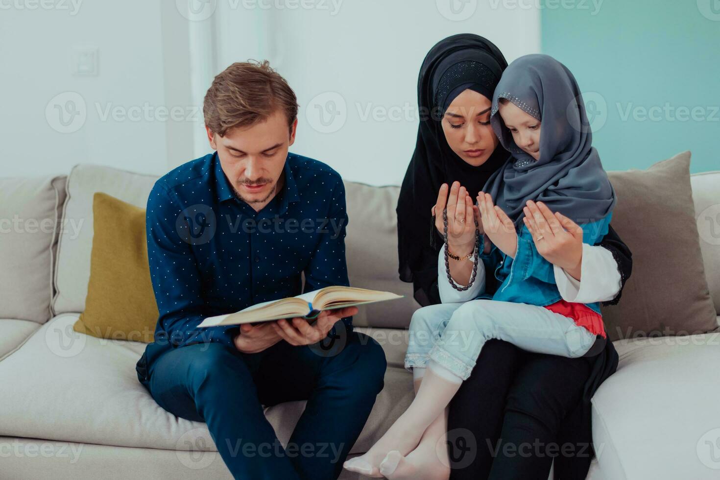 contento musulmano famiglia godendo il santo mese di Ramadan mentre preghiere e lettura il Corano insieme nel un' moderno casa foto