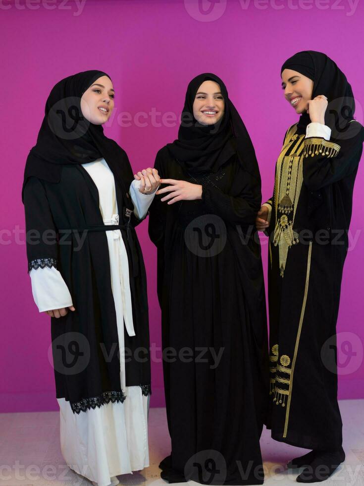 gruppo ritratto di bellissimo musulmano donne Due di loro nel alla moda vestito con hijab isolato su rosa sfondo che rappresentano moderno Islam moda e Ramadan kareem concetto foto