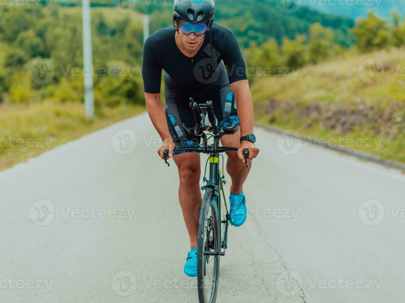 pieno lunghezza ritratto di un attivo triatleta nel abbigliamento sportivo e con un' protettivo casco equitazione un' bicicletta. selettivo messa a fuoco foto