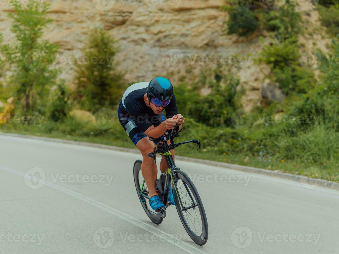 pieno lunghezza ritratto di un attivo triatleta nel abbigliamento sportivo e con un' protettivo casco equitazione un' bicicletta. selettivo messa a fuoco foto