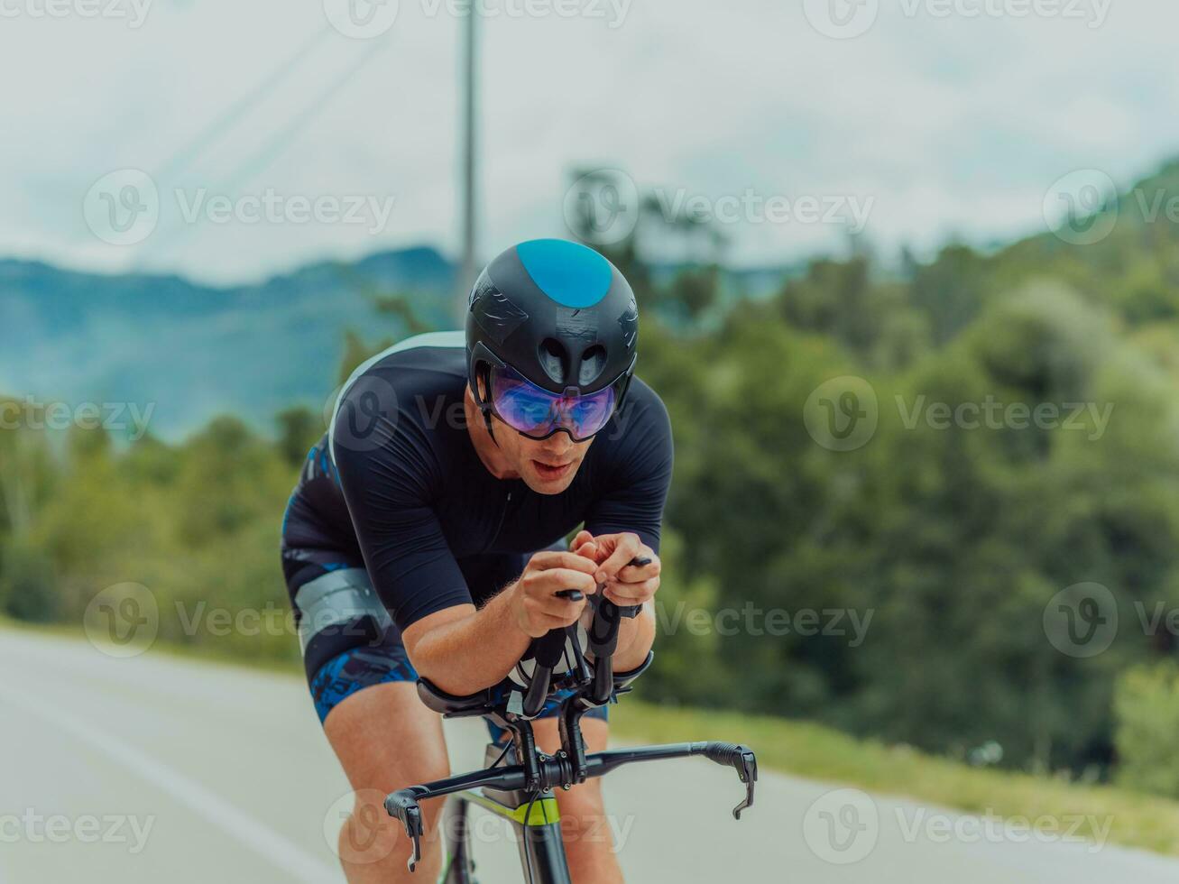 pieno lunghezza ritratto di un attivo triatleta nel abbigliamento sportivo e con un' protettivo casco equitazione un' bicicletta. selettivo messa a fuoco foto