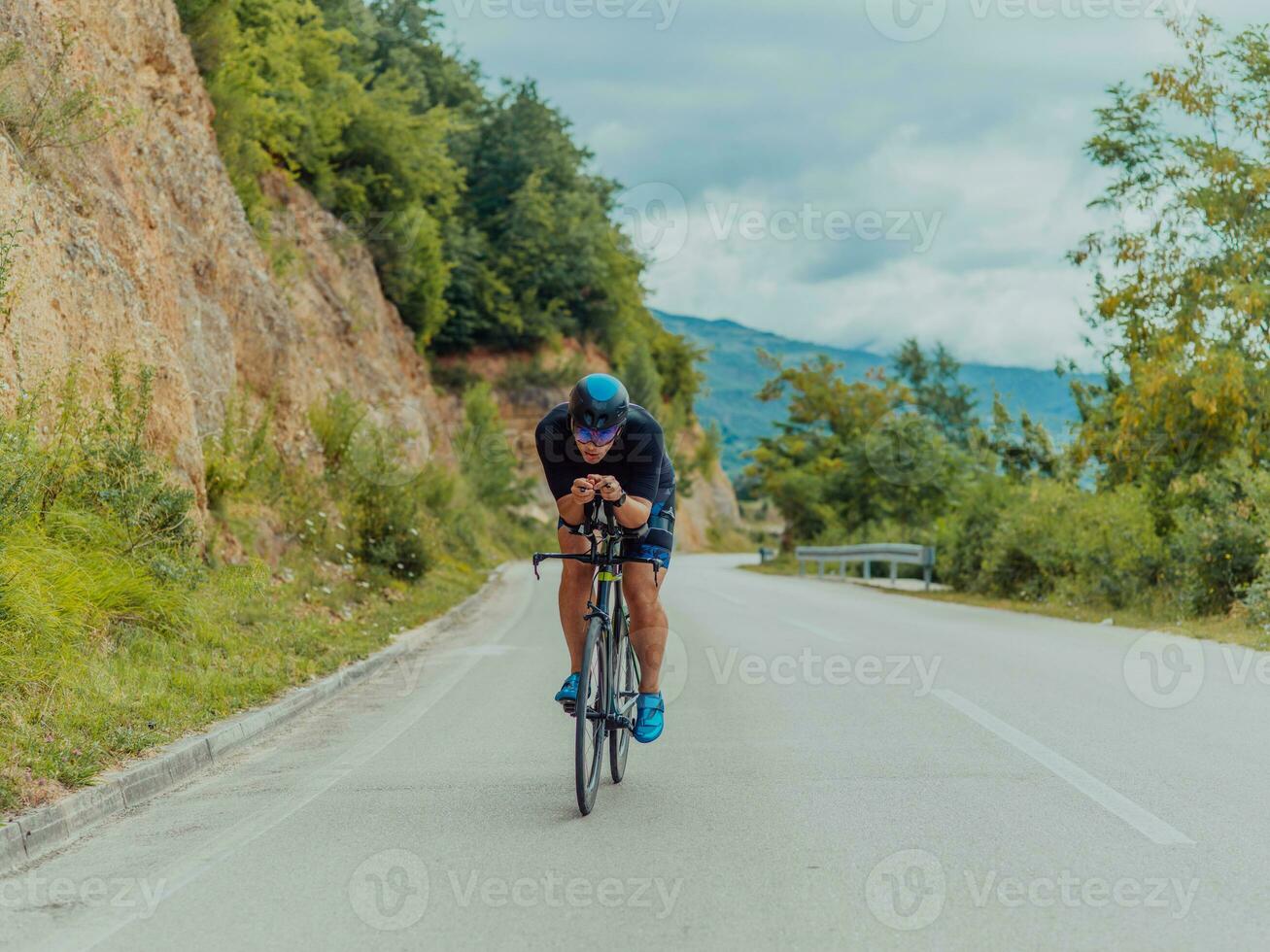 pieno lunghezza ritratto di un attivo triatleta nel abbigliamento sportivo e con un' protettivo casco equitazione un' bicicletta. selettivo messa a fuoco foto