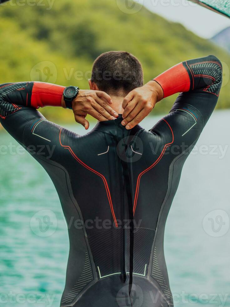 atleta mettendo su un' nuoto completo da uomo e preparazione per Triathlon nuoto e formazione nel il fiume circondato di naturale verdura foto