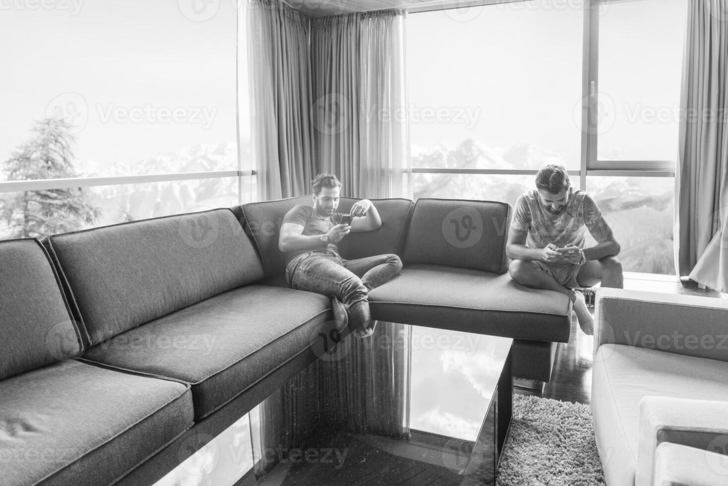 Due giovane uomini utilizzando un' mobile telefoni a casa foto