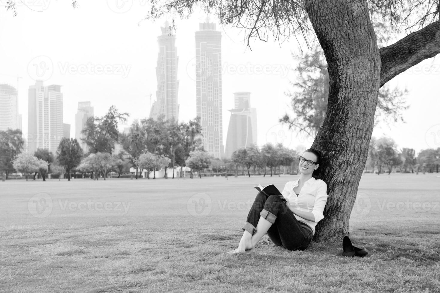 giovane donna che legge un libro nel parco foto