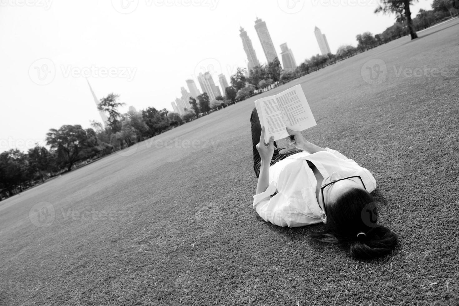 giovane donna che legge un libro nel parco foto