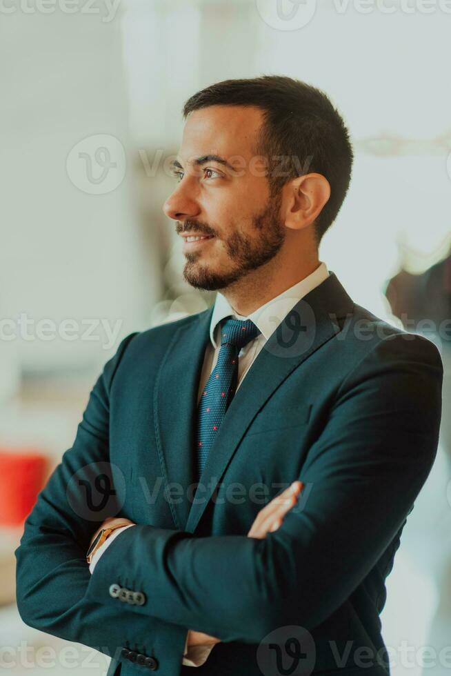 ritratto di un' uomo d'affari nel un' completo da uomo con il suo braccia attraversato nel un' moderno ufficio edificio foto