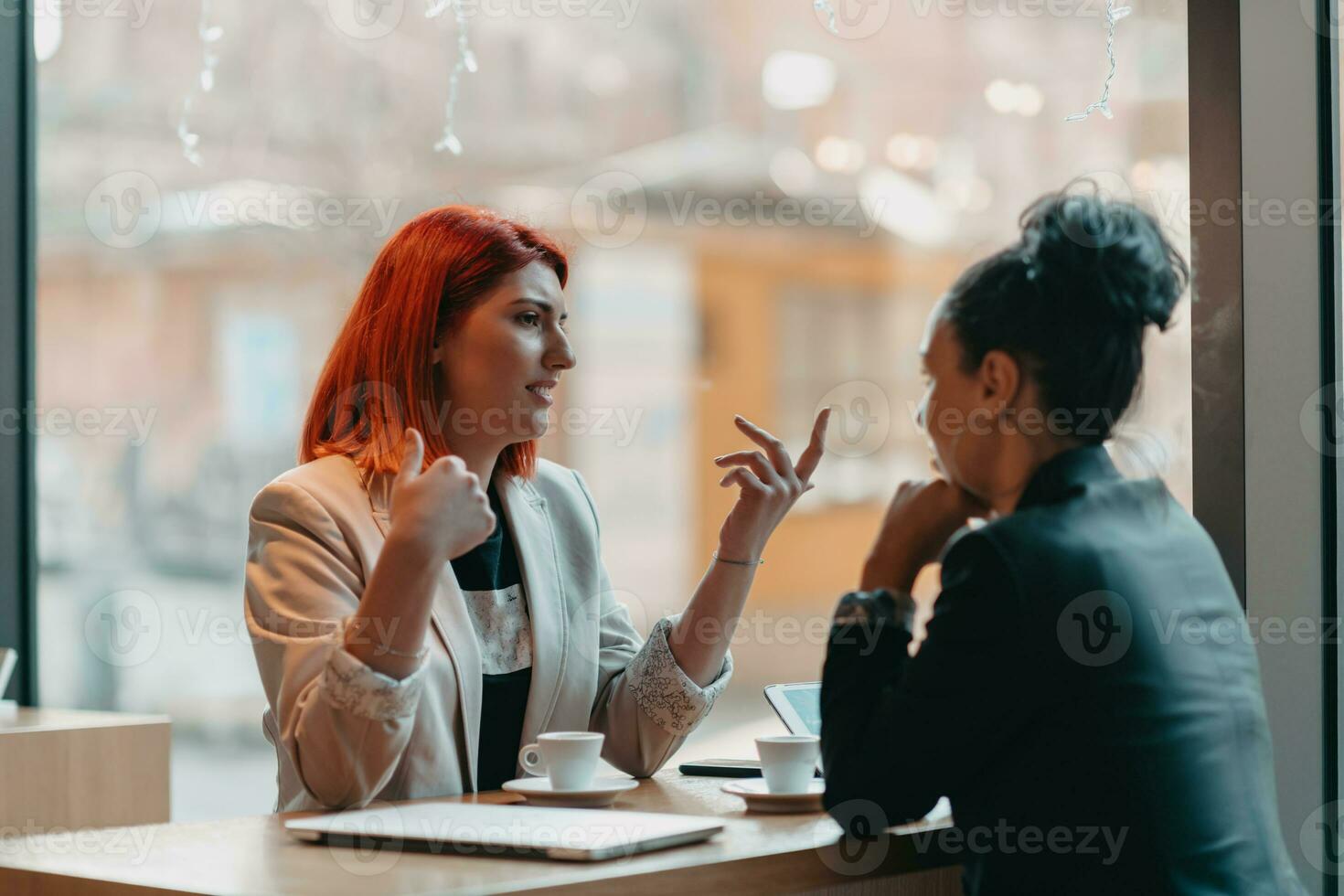 Due giovane attività commerciale donne seduta a tavolo nel bar. ragazza Spettacoli collega informazione su il computer portatile schermo. ragazza utilizzando smartphone, blogging. lavoro di squadra, attività commerciale incontro. foto