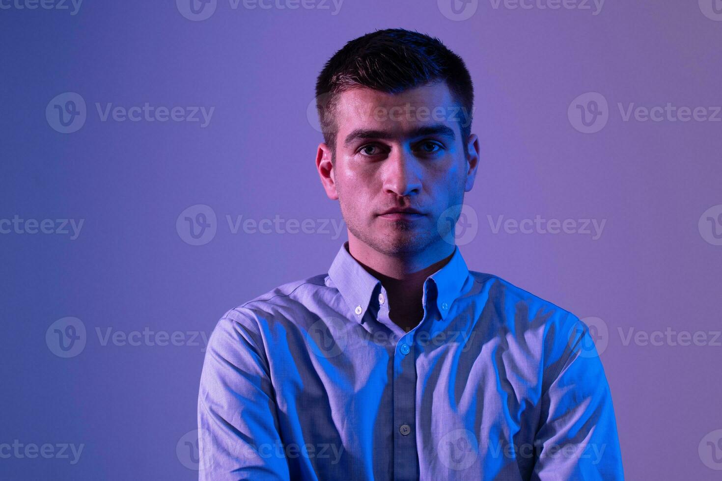 un' uomo nel un' camicia pose su un' buio multicolore neon sfondo foto