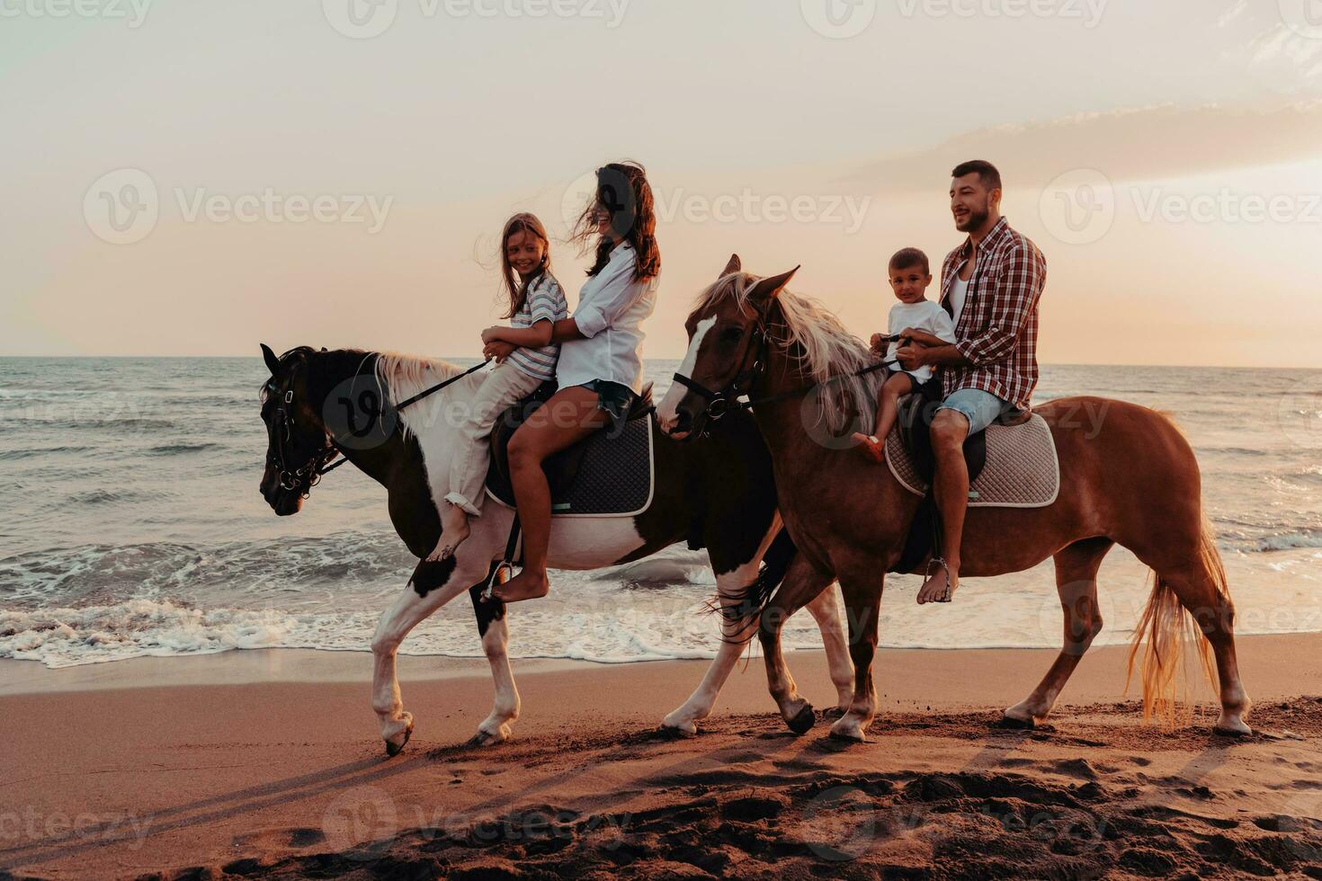 il famiglia spende tempo con loro bambini mentre equitazione cavalli insieme su un' sabbioso spiaggia. selettivo messa a fuoco foto