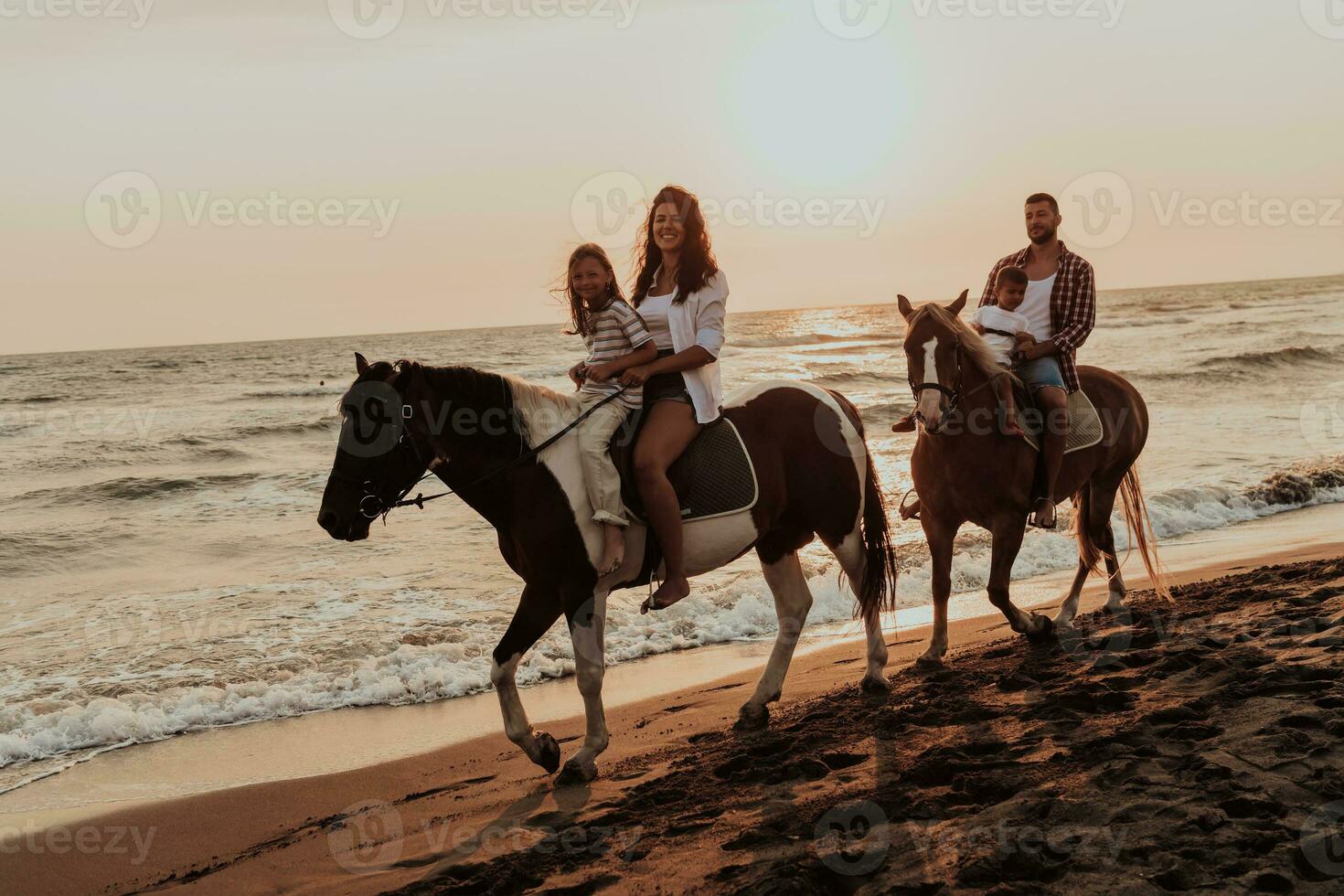 il famiglia spende tempo con loro bambini mentre equitazione cavalli insieme su un' sabbioso spiaggia. selettivo messa a fuoco foto