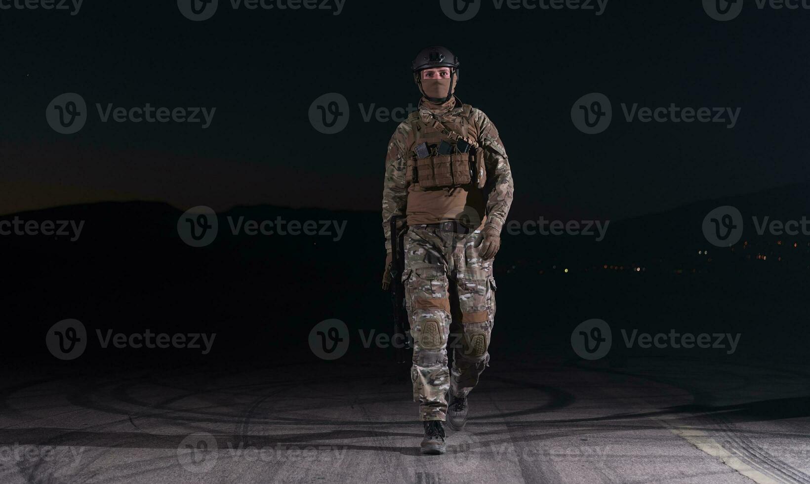 esercito soldato nel combattere uniformi con un assalto fucile, piatto vettore e combattere casco andando su un' pericoloso missione su un' piovoso notte. foto