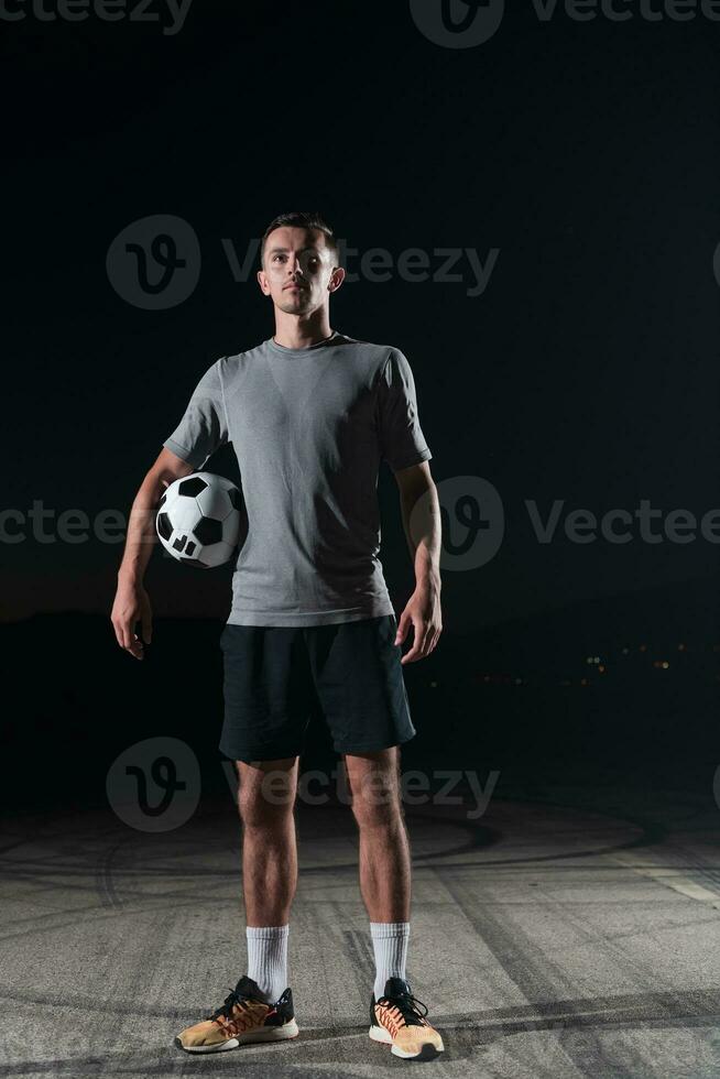 ritratto di un' giovane bello calcio giocatore uomo su un' strada giocando con un' calcio sfera. foto