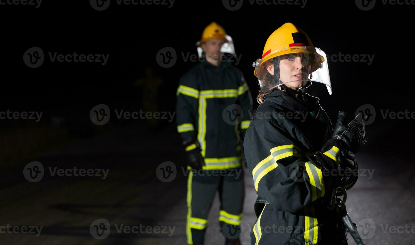 i vigili del fuoco utilizzando un' acqua tubo flessibile per eliminare un' fuoco rischio. squadra di femmina e maschio pompiere nel pericoloso salvare missione. foto