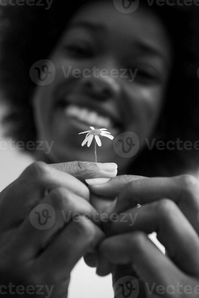 ritratto di ragazza afroamericana con un fiore in mano foto