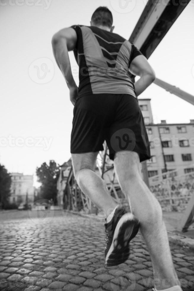 uomo che fa jogging attraverso il ponte al mattino soleggiato foto