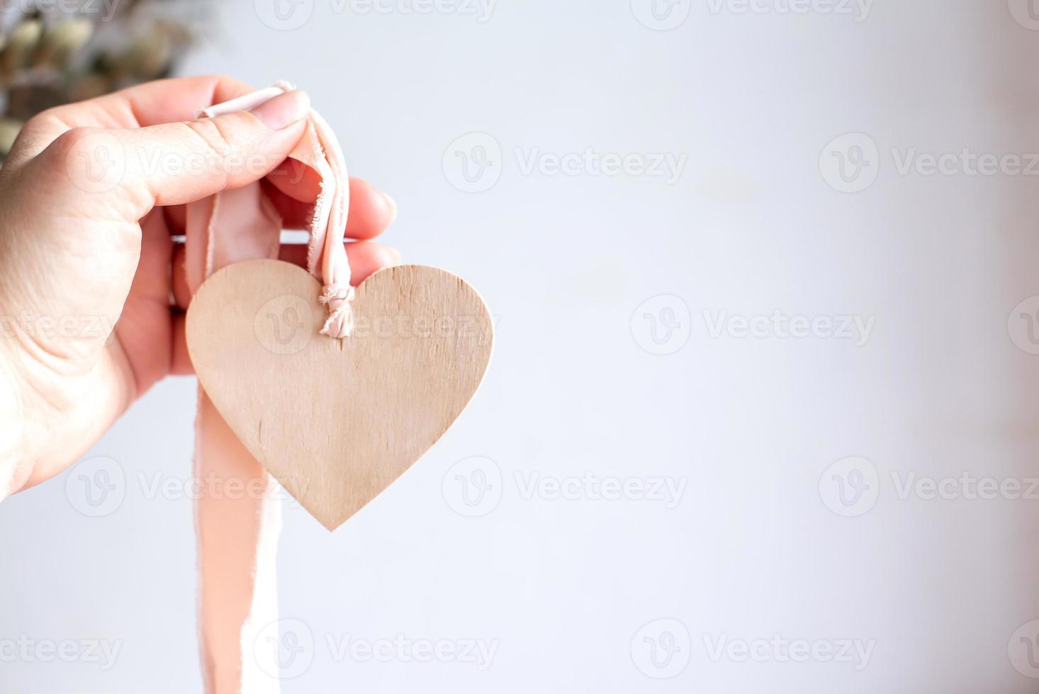 cuore di legno su nastro rosa. mano che tiene il cuore di legno. copia spazio. foto