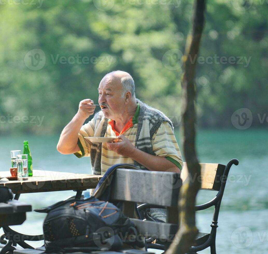 anziano uomo mangiare dolce a all'aperto ristorante foto