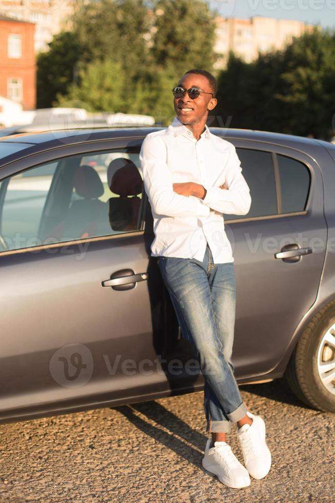 felice afroamericano accanto a un'auto in estate foto