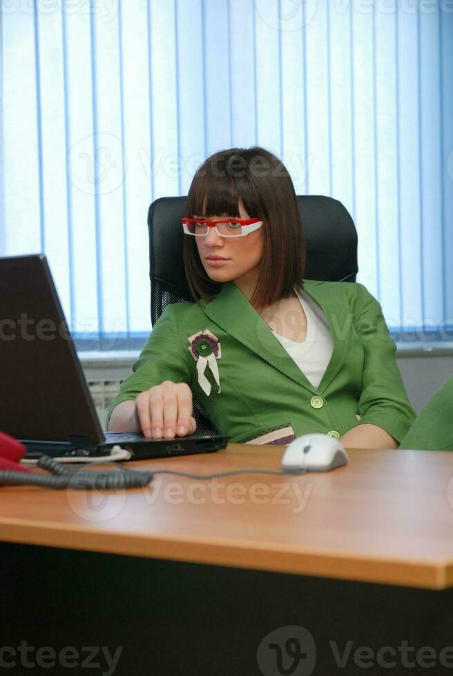 sorridente giovane donna d'affari Lavorando su un' il computer portatile nel il ufficio. foto