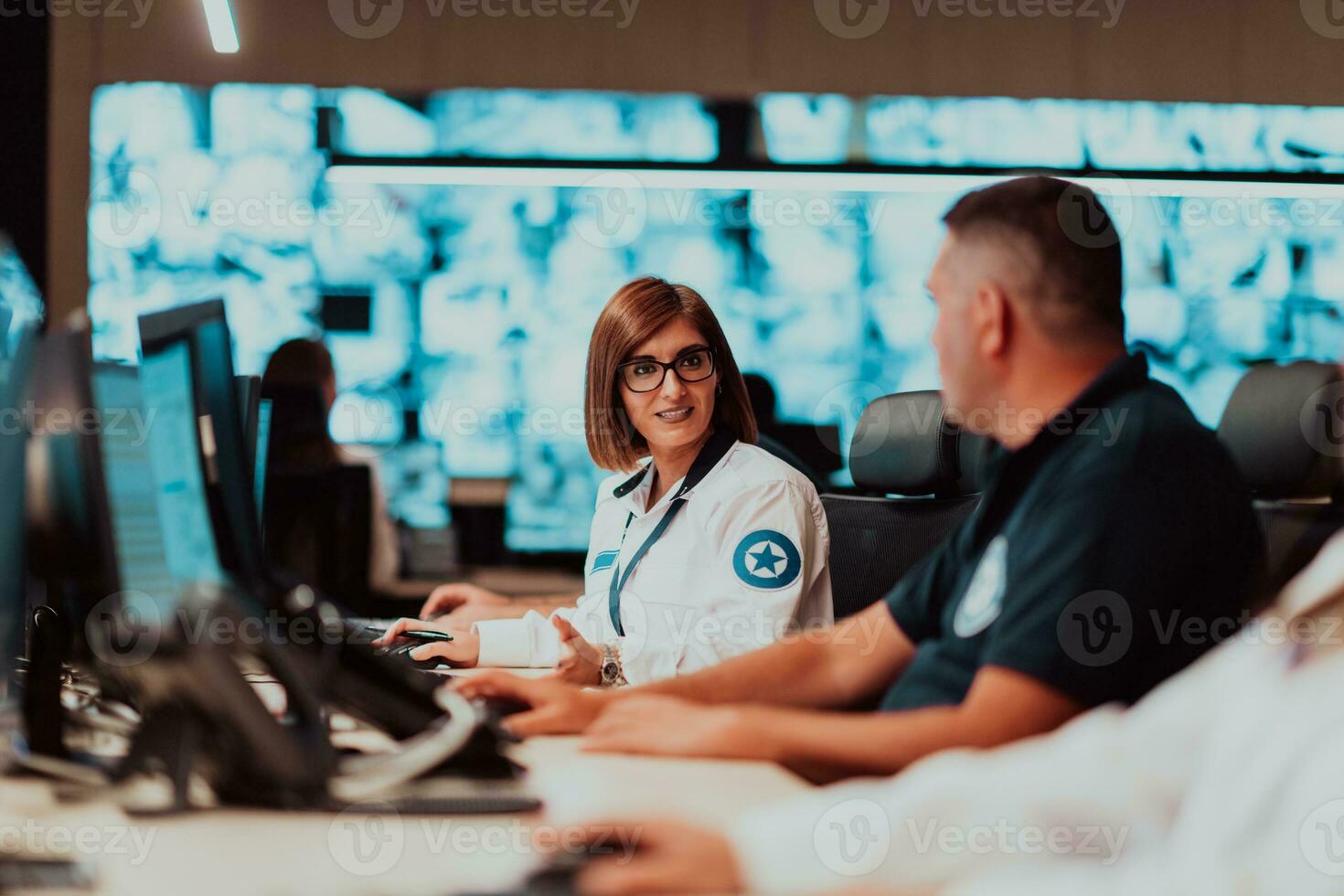 gruppo di sicurezza dati centro operatori Lavorando nel un' cctv monitoraggio camera guardare su multiplo monitor ufficiali monitoraggio multiplo schermi per sospetto attività squadra Lavorando su il sistema contr foto