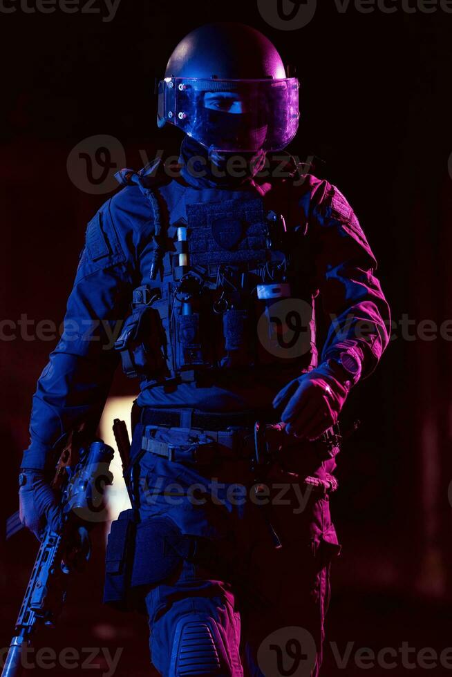 esercito soldato nel combattere uniformi con un assalto fucile e combattere casco notte missione buio sfondo. blu e viola gel leggero effetto. foto