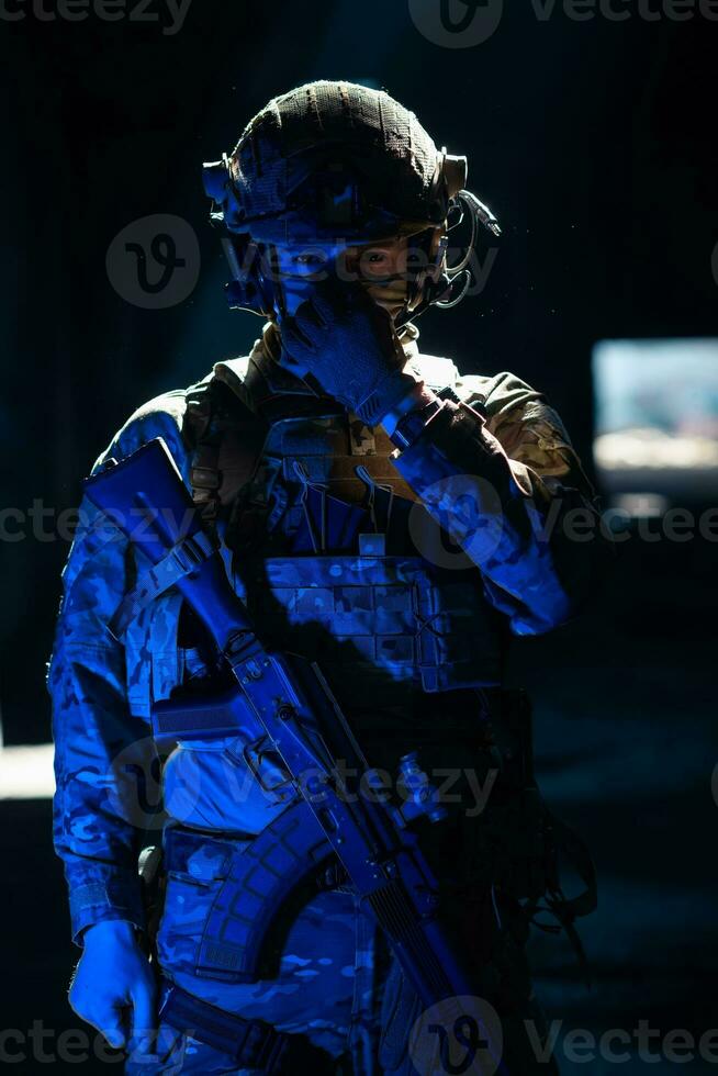 esercito soldato nel combattere uniformi con un assalto fucile e combattere casco notte missione buio sfondo. blu e viola gel leggero effetto. foto