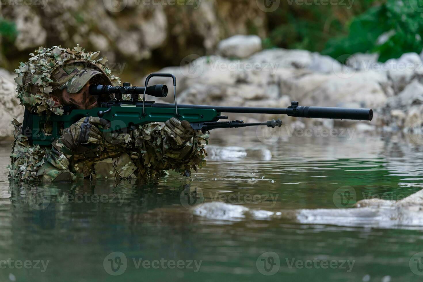 un' militare uomo o softair giocatore nel un' camuffare completo da uomo Sneaking il fiume e obiettivi a partire dal un' cecchino fucile per il lato o per obbiettivo. foto