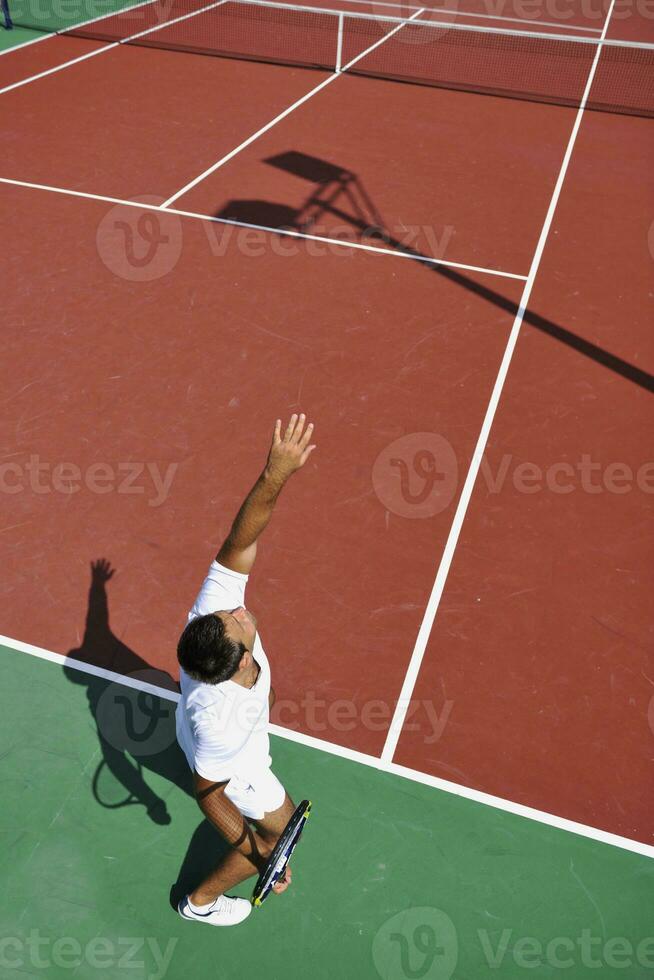 il giovane gioca a tennis all'aperto foto