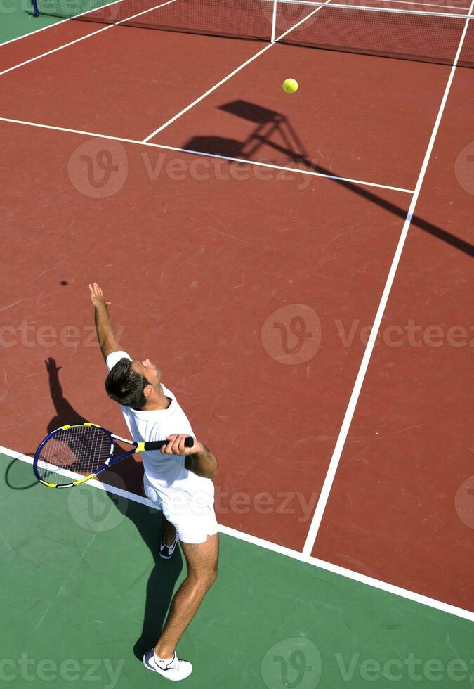 il giovane gioca a tennis all'aperto foto